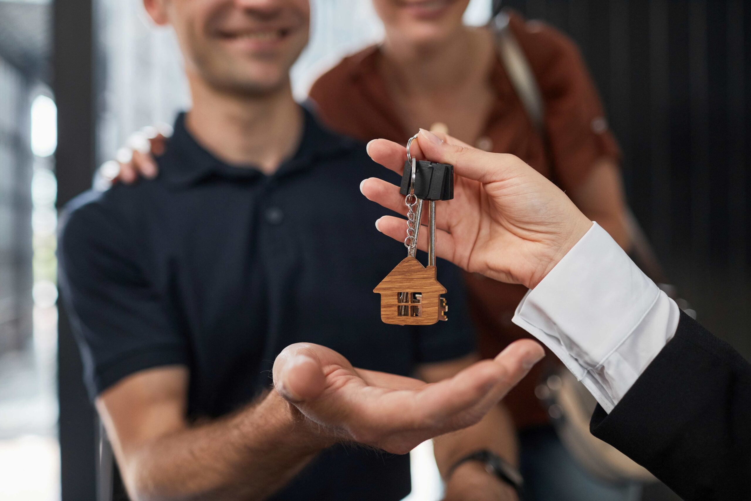 Nahaufnahme eines Immobilienmaklers, der Schlüssel zum Paar gibt, mit Fokus auf Hausschlüsselbund, Kopierraum